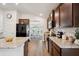 Modern kitchen features granite counters, stainless appliances, wood cabinets, and a breakfast bar looking into the dining room at 2085 Pecos Dr, Kissimmee, FL 34759