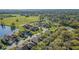 An aerial view of a neighborhood showcases beautiful homes alongside a peaceful lake and green fields on a sunny day at 2987 Mission Lakes Dr # 10, Lakeland, FL 33803