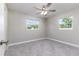 Cozy bedroom with gray carpet, two bright windows, and a modern ceiling fan at 300 Senate St, Auburndale, FL 33823