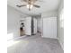 Bedroom with gray carpet, ceiling fan and view of an adjacent kitchen and laundry room at 300 Senate St, Auburndale, FL 33823