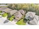 Aerial view of a tan home with a brick driveway surrounded by green grass, trees, and nearby homes at 4759 Lathloa Loop, Lakeland, FL 33811