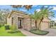 Charming home featuring a stone facade, well-manicured lawn, and beautiful landscaping with mature palm trees at 4759 Lathloa Loop, Lakeland, FL 33811