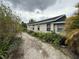 Side view of home with gravel driveway and abundant ferns and shrubbery at 5636 Old Highway 37, Lakeland, FL 33811