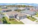 Aerial view of the gray single-story home featuring a well-manicured lawn, landscaping, and a three car garage at 6185 Gracie Pl, Lakeland, FL 33812