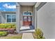 Close-up of a red double-door entryway with sidelights, set in a gray home with manicured landscaping at 6185 Gracie Pl, Lakeland, FL 33812