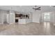 Open concept living room with tile floors, ceiling fan, and a kitchen area with dark cabinets at 6185 Gracie Pl, Lakeland, FL 33812