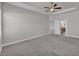 Carpeted main bedroom with a tray ceiling, ceiling fan, and an ensuite bathroom at 6185 Gracie Pl, Lakeland, FL 33812