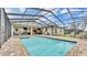 Screened pool and spa combo with brick flooring, surrounded by green trees and a fence at 6923 Highlands Creek Ave, Lakeland, FL 33813