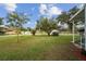 Wide view of the front yard of this home with mature trees, a green lawn, and updated landscaping at 1115 S Virginia Ave, Bartow, FL 33830