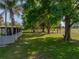 Large backyard with lush green grass and mature trees offering shade and privacy in a serene outdoor setting at 121 Greenfield Rd, Winter Haven, FL 33884