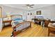 Cozy bedroom features a wooden bed frame, ceiling fan, a study desk and hardwood floors at 121 Greenfield Rd, Winter Haven, FL 33884