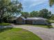 Charming single-story home featuring a stone facade, solar panels, mature trees, and a spacious driveway at 121 Greenfield Rd, Winter Haven, FL 33884