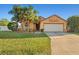 Inviting single-story home featuring a two-car garage, lush lawn, and mature palm trees enhancing its curb appeal at 404 Emerald Cove Loop, Lakeland, FL 33813