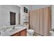 Well-lit bathroom featuring a sink with wood cabinets, toilet, and a shower with a beige curtain at 4512 Brookshire Pl, Lake Wales, FL 33898