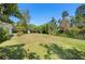 Expansive backyard with lush green grass, mature trees, and a shed with a bright blue sky above at 4908 S Bedford Ln, Lakeland, FL 33813