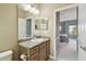 Bathroom featuring granite counters, wood cabinets, a large mirror, and a view into the bedroom at 4929 Tennessee Lake Dr, Auburndale, FL 33823