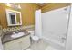 Traditional bathroom featuring a tub-shower combo with white tile, a white vanity, and gold wallpaper at 502 Lake Harris Dr, Lakeland, FL 33813