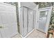 Bathroom boasts a framed glass shower, leafy wallpaper, access to outside, and white painted doors at 502 Lake Harris Dr, Lakeland, FL 33813