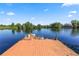 Panoramic view of a wooden dock on a calm lake with trees dotting the shoreline under a blue sky at 502 Lake Harris Dr, Lakeland, FL 33813