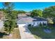 Back of house view featuring a two-car garage, a driveway, and a spacious yard with mature trees, showcasing curb appeal at 5730 Tanasi Ct, Lakeland, FL 33812