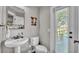 Charming powder room with pedestal sink, decorative mirror, and natural light from the window at 6383 Summertimes Plantation Blvd, Bartow, FL 33830