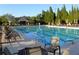 A community pool is surrounded by lounge chairs, tables, and tall trees at 6515 Eagle View Loop, Lakeland, FL 33813