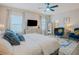 Well-lit bedroom boasts a ceiling fan, mounted TV, sitting area and ensuite bathroom at 7289 Liberty Rd, Lakeland, FL 33809