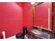A modern bathroom with a black toilet, marble vanity, and red walls at 14 Casarena Ct, Winter Haven, FL 33881