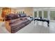 Comfortable living room with a brown leather sofa, white tiled floors, and sliding glass doors to the outside at 14 Casarena Ct, Winter Haven, FL 33881