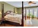 Spacious main bedroom with hardwood floors, a four-poster bed, and French doors to a private balcony at 14 Casarena Ct, Winter Haven, FL 33881