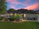 Twilight view of the private backyard with screened-in pool, lush landscaping, and colorful sunset at 152 Melissa Trl, Auburndale, FL 33823