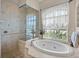 Elegant bathroom featuring tub, glass shower, and large window with natural light at 152 Melissa Trl, Auburndale, FL 33823