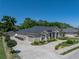 Beige single-Gathering home with a gray roof, manicured shrubs, and a three-car garage, surrounded by greenery at 152 Melissa Trl, Auburndale, FL 33823