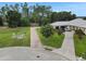 Well-maintained front yard with flowering trees, lush lawn, and a spacious driveway leading to a multi-car garage at 152 Melissa Trl, Auburndale, FL 33823