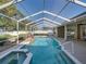 Sparkling screened-in pool with rock waterfall feature, hot tub, and spacious deck with ceiling fan at 152 Melissa Trl, Auburndale, FL 33823