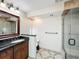 This bathroom provides a vanity with dark countertop, glass-enclosed shower, and neutral tile at 2605 Nevada Rd, Lakeland, FL 33803