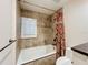 Bathroom with a tiled tub and shower featuring a red patterned curtain and a granite vanity at 2605 Nevada Rd, Lakeland, FL 33803