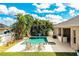 Backyard with a pool featuring mosaic tile accents, lounge chairs, lush tropical trees, and an outdoor kitchen at 2814 Sheldon St, Lakeland, FL 33813