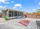 Exterior view of the screen enclosed porch and backyard featuring mature landscaping, deck, and a hot tub at 300 Keswick Ave, Davenport, FL 33897