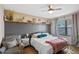 Comfortable main bedroom featuring a ceiling fan, hardwood floors, and textured wall with floating shelves at 301 St Georges Cir, Eagle Lake, FL 33839