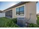 Close-up of the backyard, featuring a screened lanai, well-maintained lawn, and an efficient AC unit at 4189 Marseille Ln, Lakeland, FL 33810