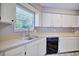 Kitchen area featuring stainless steel sink under window with wood countertops and white cabinets and black dishwasher at 4228 Sunny Land Dr, Lakeland, FL 33813