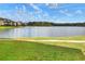 Serene lake view from the backyard with manicured green lawn and a row of colorful houses at 4488 Whistlewood Cir, Lakeland, FL 33811