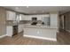 Well-lit kitchen featuring white cabinets, stainless steel appliances, an island, and wood-look floors at 45 Powell Rd, Winter Haven, FL 33880