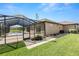 Exterior view of home with screened patio and pool, surrounded by green lawn at 5020 Truman Ln, Lakeland, FL 33812