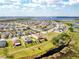 Wide aerial perspective of houses in a suburban community, complete with ponds and green spaces under a partly cloudy sky at 661 Black Eagle Dr, Groveland, FL 34736