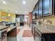 Open-concept kitchen with stainless appliances, dark cabinets, and granite countertops seamlessly flowing into the dining area at 661 Black Eagle Dr, Groveland, FL 34736