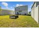 Backyard of a two-story home with a grass lawn, block firepit, and patio area at 728 Trotters Dr, Eagle Lake, FL 33839