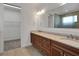 Bathroom showcasing double vanity with granite counters, a large mirror, and shower at 7947 Lake James Blvd, Lakeland, FL 33810