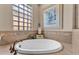 A large, white soaking tub is set beneath a window, next to a framed painting in this bathroom at 914 Christina Chase Dr # Drive, Lakeland, FL 33813